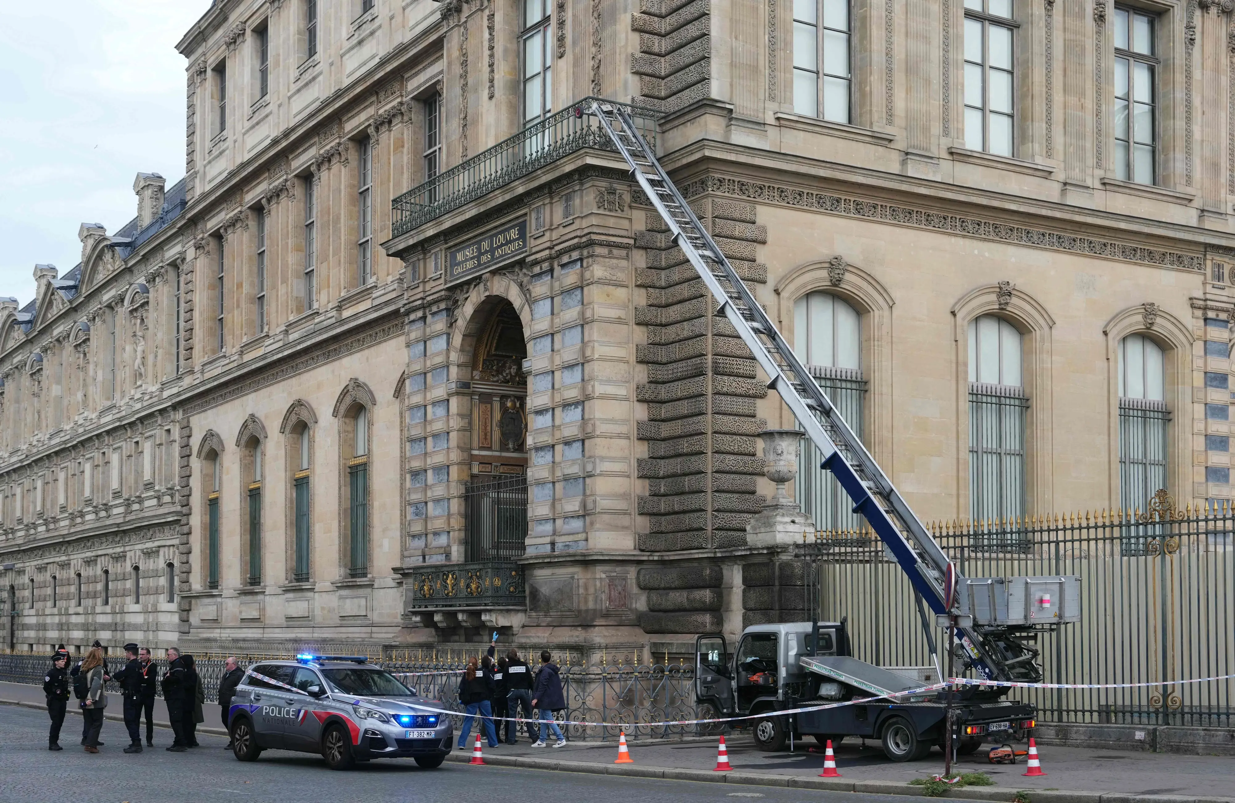 French police officers stand next to a furniture elevator used by robbers to enter the Louvre Museum | AFP