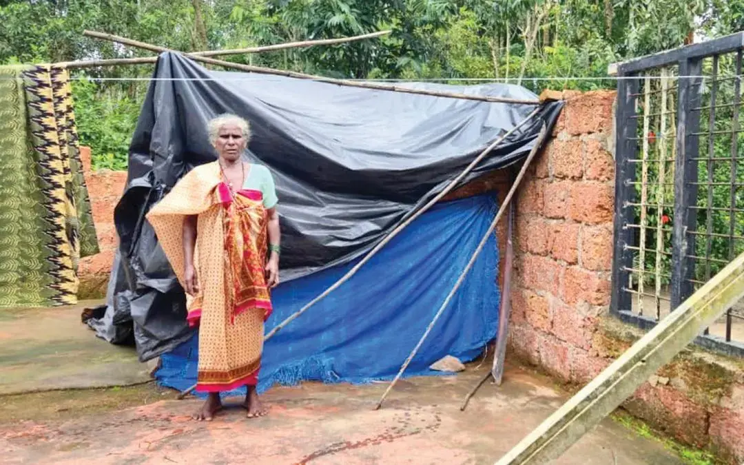 Kali Mallan stands near the tarpaulin sheets that have been erected over the remains of her destroyed home