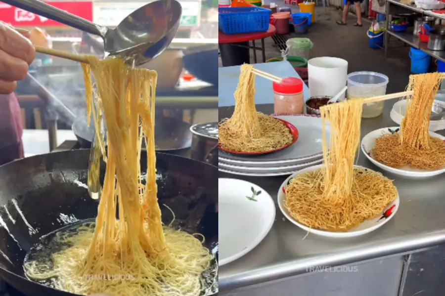 Flying Noodles preparation in a Malaysian street food stall, showing noodles held vertically by chopsticks