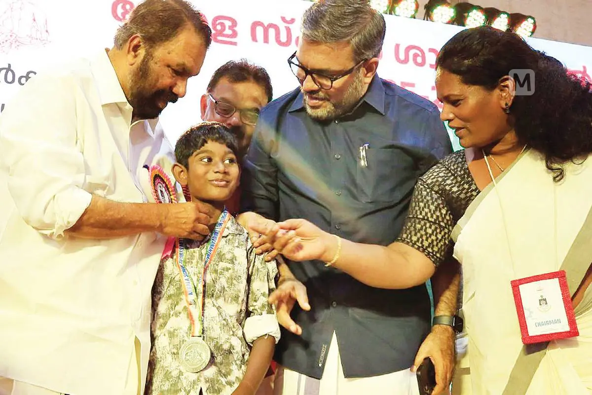 സംസ്ഥാന സ്കൂൾ കായികമത്സരത്തിൽ ലഭിച്ച മെഡൽ നഷ്ടപ്പെട്ട ഹാഷിമിന് മന്ത്രി വി. ശിവൻകുട്ടി പുതിയ മെഡൽ നൽകുന്നു