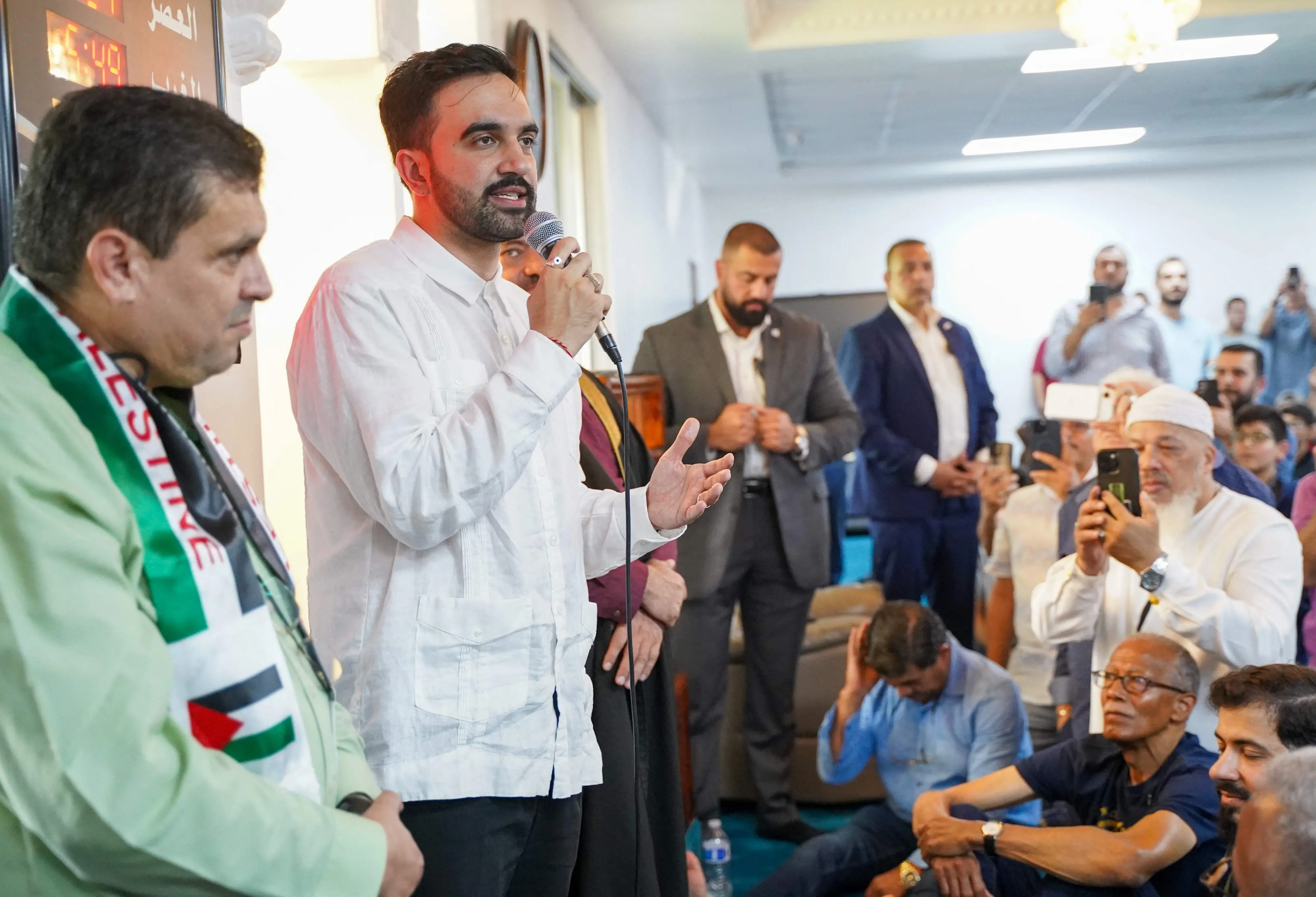 New York City Mayor-elect Zohran Mamdani in white shirt, speaks to members of the Centro Islamico del Caribe -Masjid Ebadur Rahman mosque in prayer on November 7 | Photo: AFP