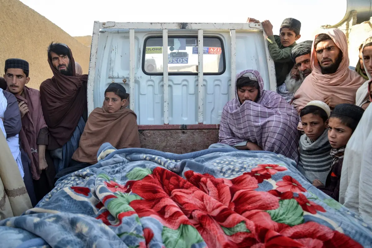 Afghan men sit beside the dead bodies of victims who were killed following cross-border fire from Pakistan, in the back of a truck | Photo: AFP