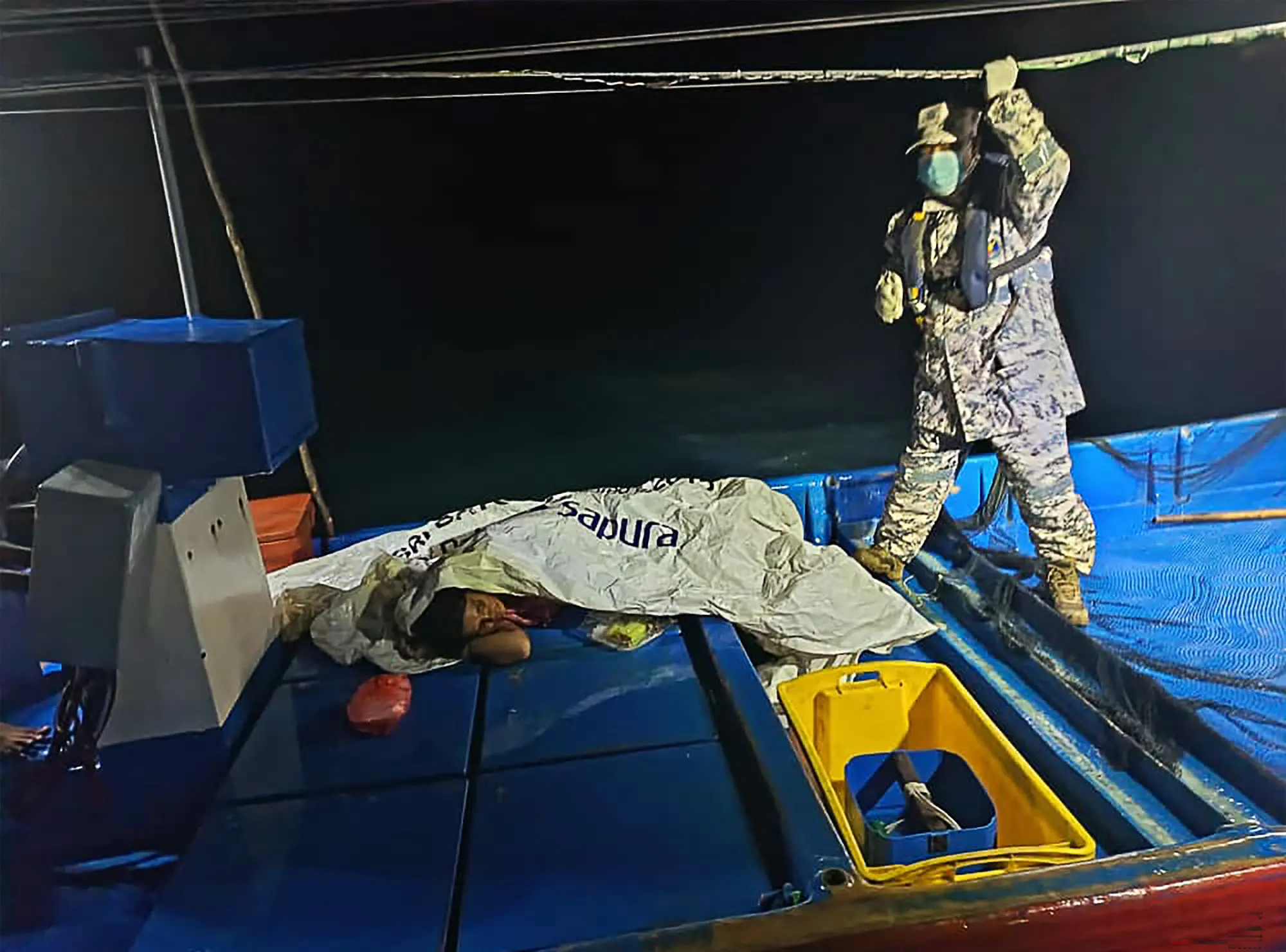 A MMEA staff member checking on a survivor rescued by a fishing boat during a search and rescue operation off the coast of Langkawi, after a boat carrying migrants from Myanmar capsized near the Malaysia-Thailand border. | Photo: AFP