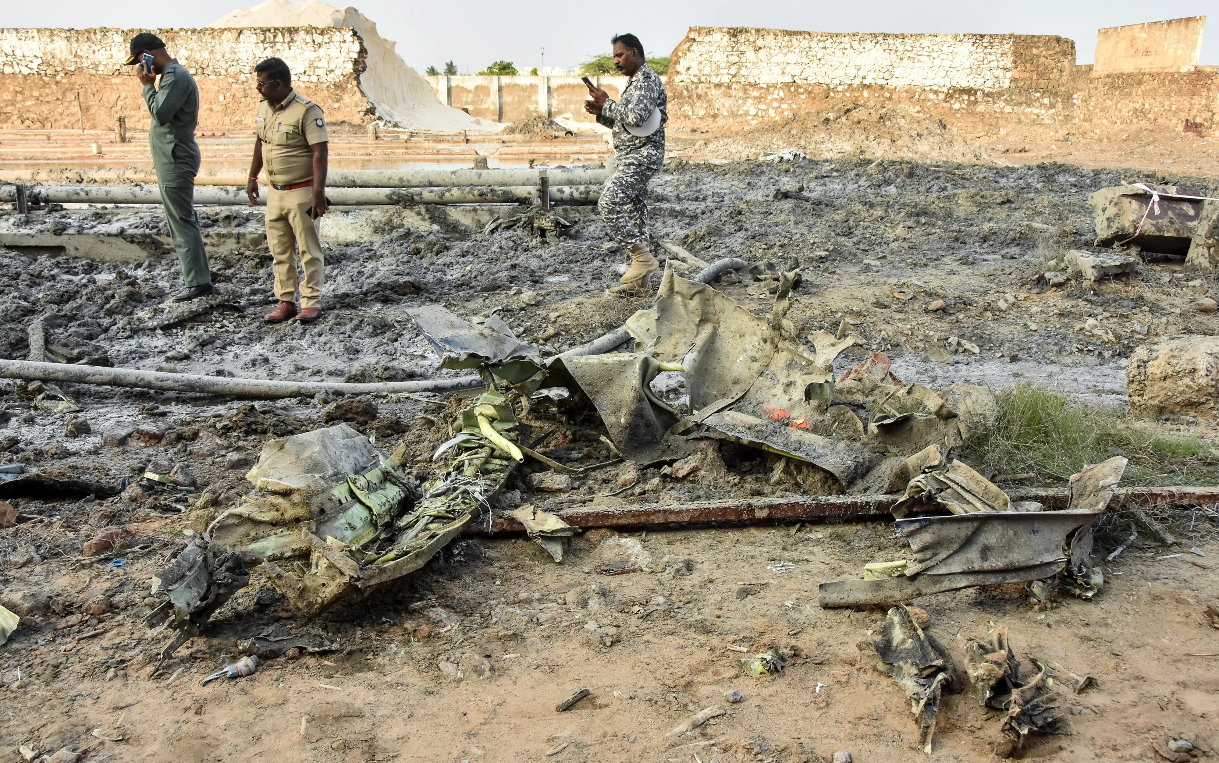 Police and Indian Air Force (IAF) personnel stand amid charred debris after an IAF aircraft 'Pilatus PC-7', which was on a routine training mission, crashed near Tambaram, in Chengalpattu district, Tamil Nadu, Friday, Nov. 14, 2025.| Photo: PTI