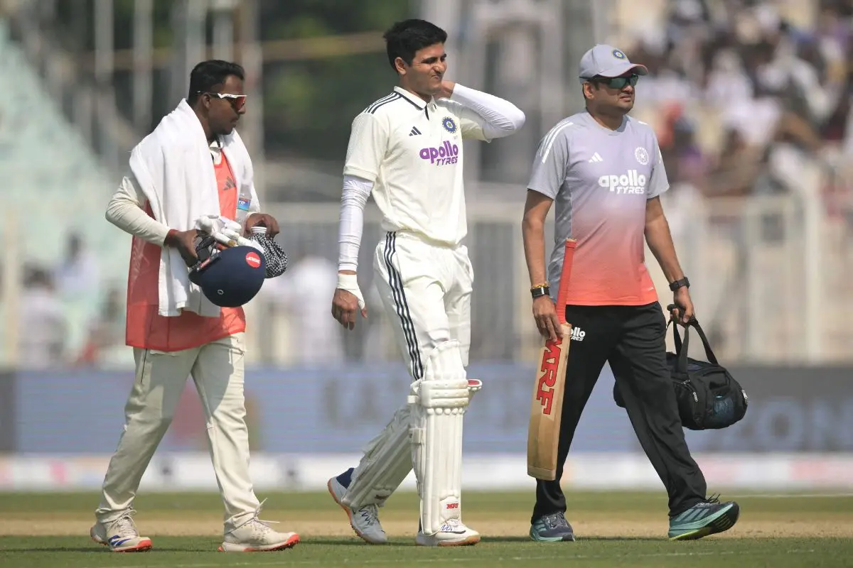 Gill (C) walks back to the pavilion after his injury. (Photo by DIBYANGSHU SARKAR / AFP)