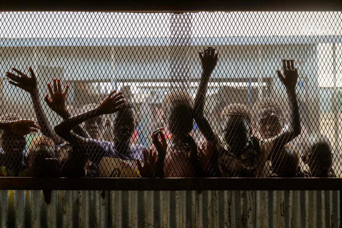 Children gather at the fenced window of a safe-space classroom managed by War Child Holland at the Renk Transit Center in Renk, South Sudan