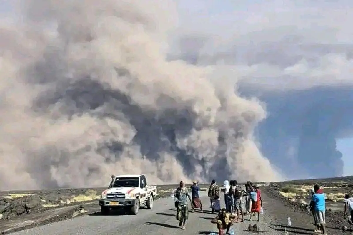 In this photo released by the Afar Government Communication Bureau, people watch ash billow from the first time eruption of the Hayli Gubbi Volcano in Ethiopia's Afar region
