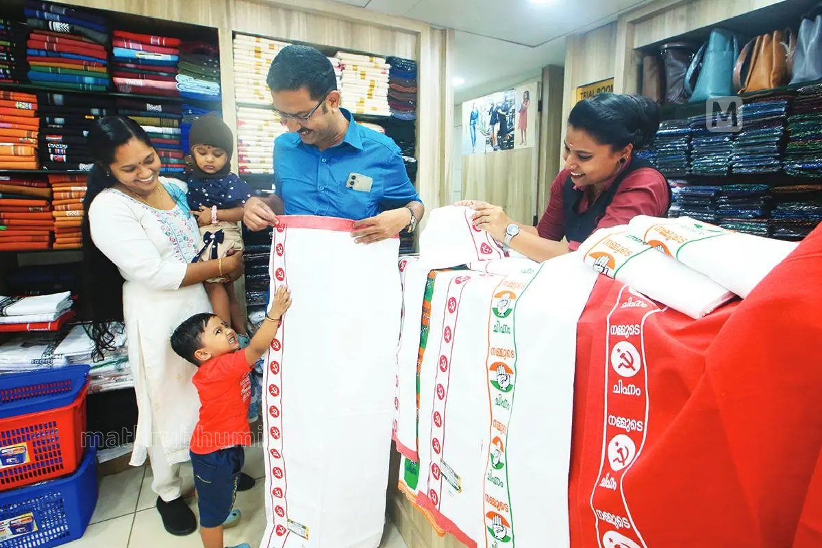 കല്പറ്റയിലെ വസ്ത്രവ്യാപാരസ്ഥാപനത്തിൽ തിരഞ്ഞെടുപ്പിനായി എത്തിച്ച വിവിധ പാർട്ടികളുടെ ചിഹ്നമുള്ള മുണ്ടുകളിൽ ഒന്ന് എടുത്തുനോക്കുന്ന കല്പറ്റ ബ്ലോക്ക് പഞ്ചായത്ത് വൈത്തിരി ഡിവിഷൻ സ്ഥാനാർഥി എം.വി. വിജേഷും കുടുംബവും.|Photo: Mathrubhumi