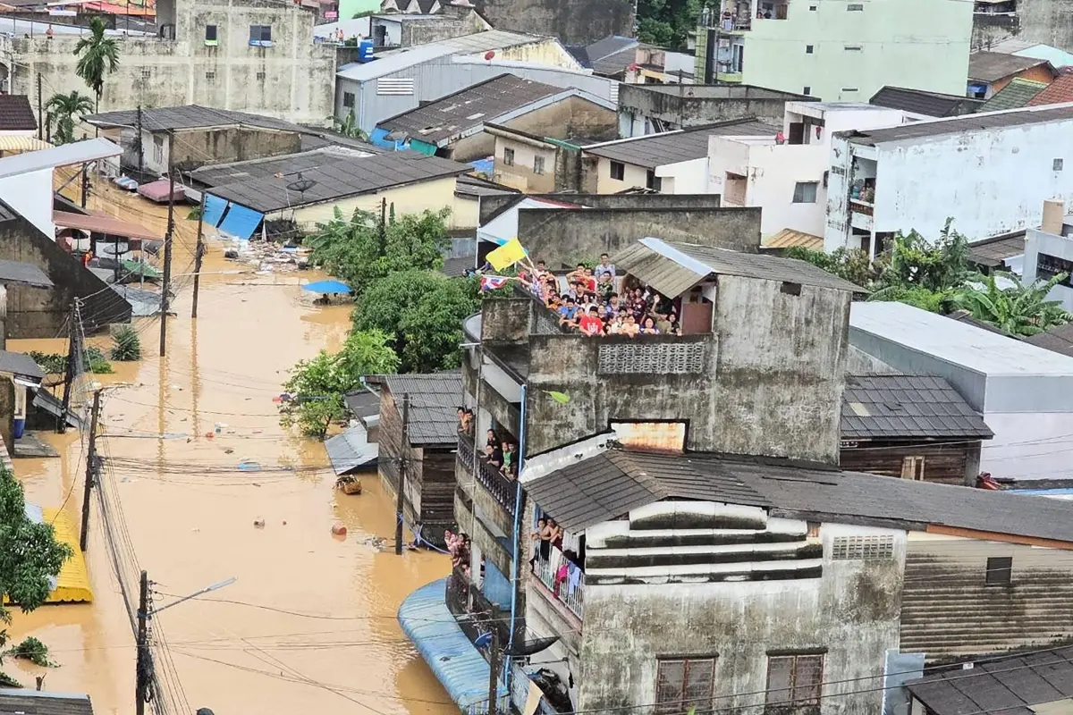 People looking out from residential buildings surrounded by flood waters in Hat Yai.
