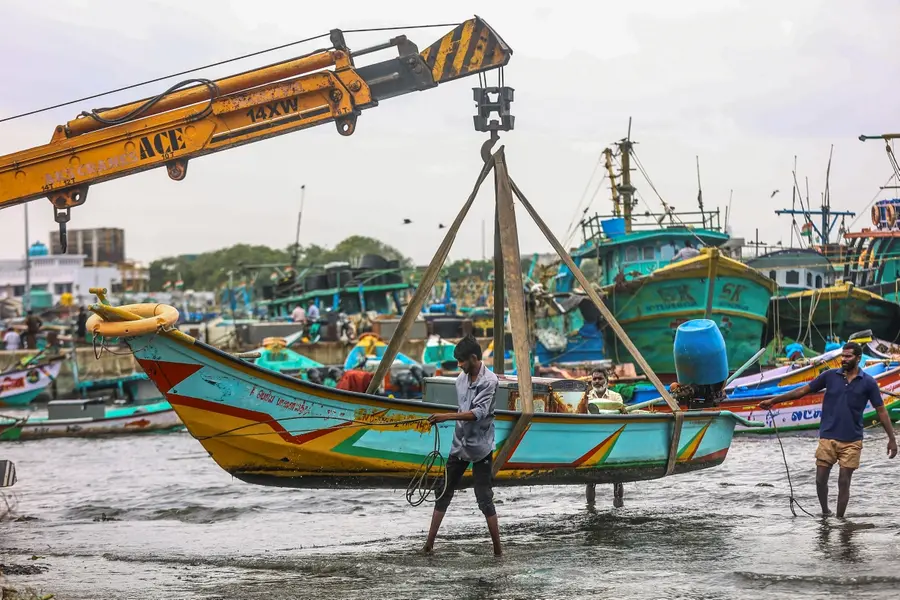 A fishing boat being carried to a safer place amid gusty winds in view of Cyclone 'Ditwah', at Kasimedu fishing harbour, in Chennai,
