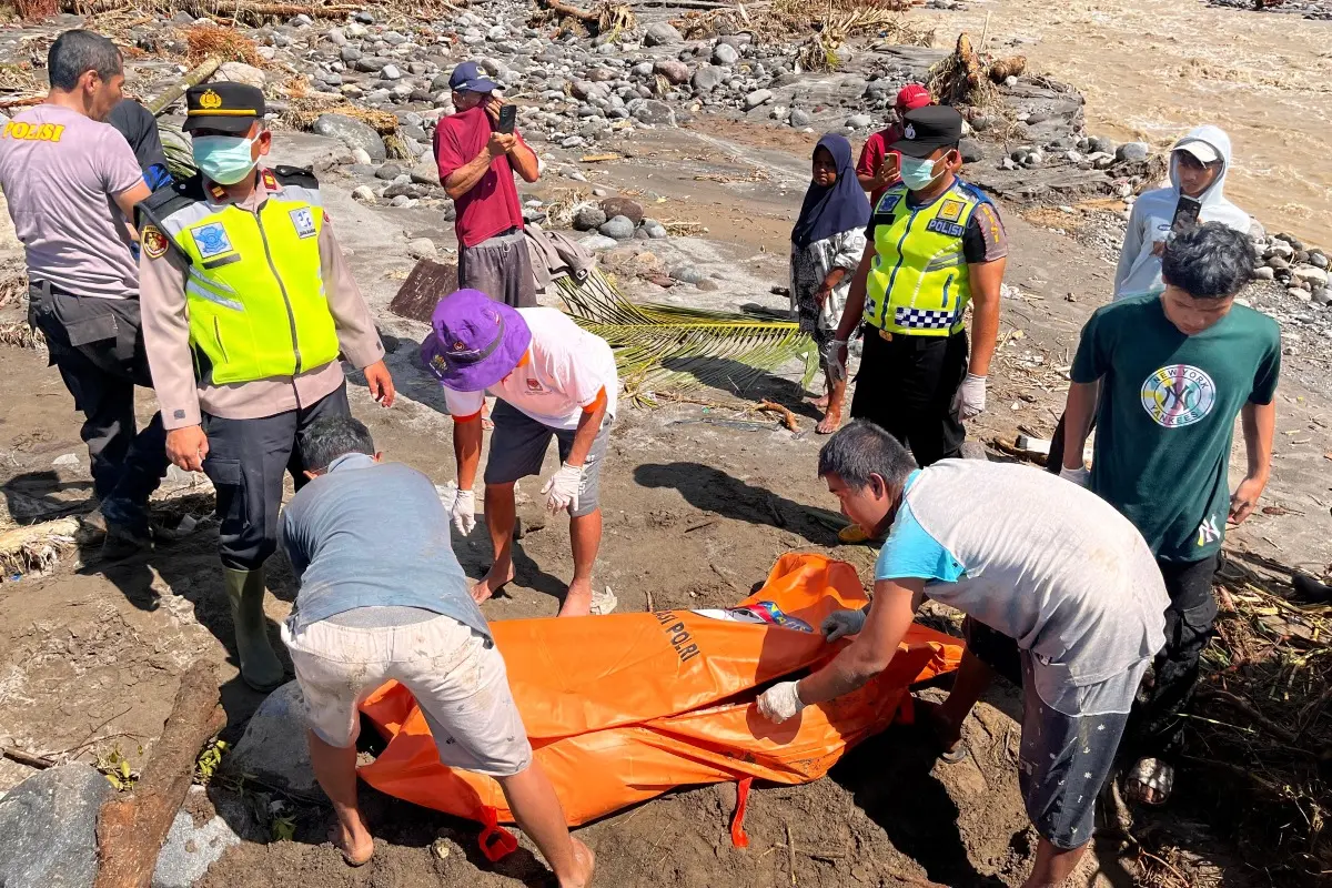 Rescuers put the body of a flood victim recovered from a river inside a body bag | Photo: AP