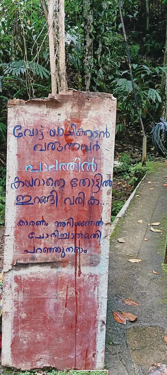 ഇരുപതേക്കറിൽ വീടിന് മുൻഭാഗത്തുള്ള പാലത്തിൽ വീട്ടുകാർ സ്ഥാനാർഥികൾക്ക് വായിക്കാൻ സ്ഥാപിച്ചിരിക്കുന്ന ബോർഡ്
