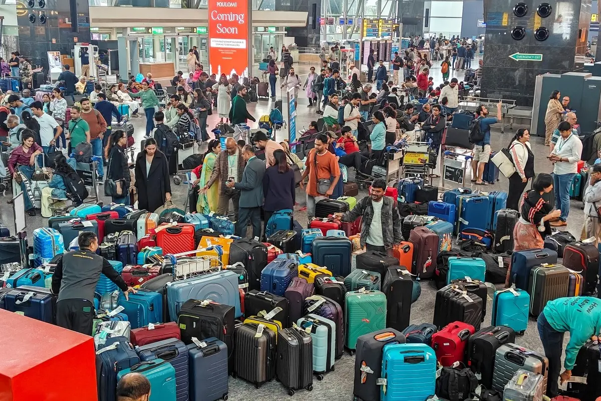 Stranded passengers search for their luggage near a counter after IndiGo cancelled more than 400 flights, at the Kempegowda International Airport, in Bengaluru, Karnataka