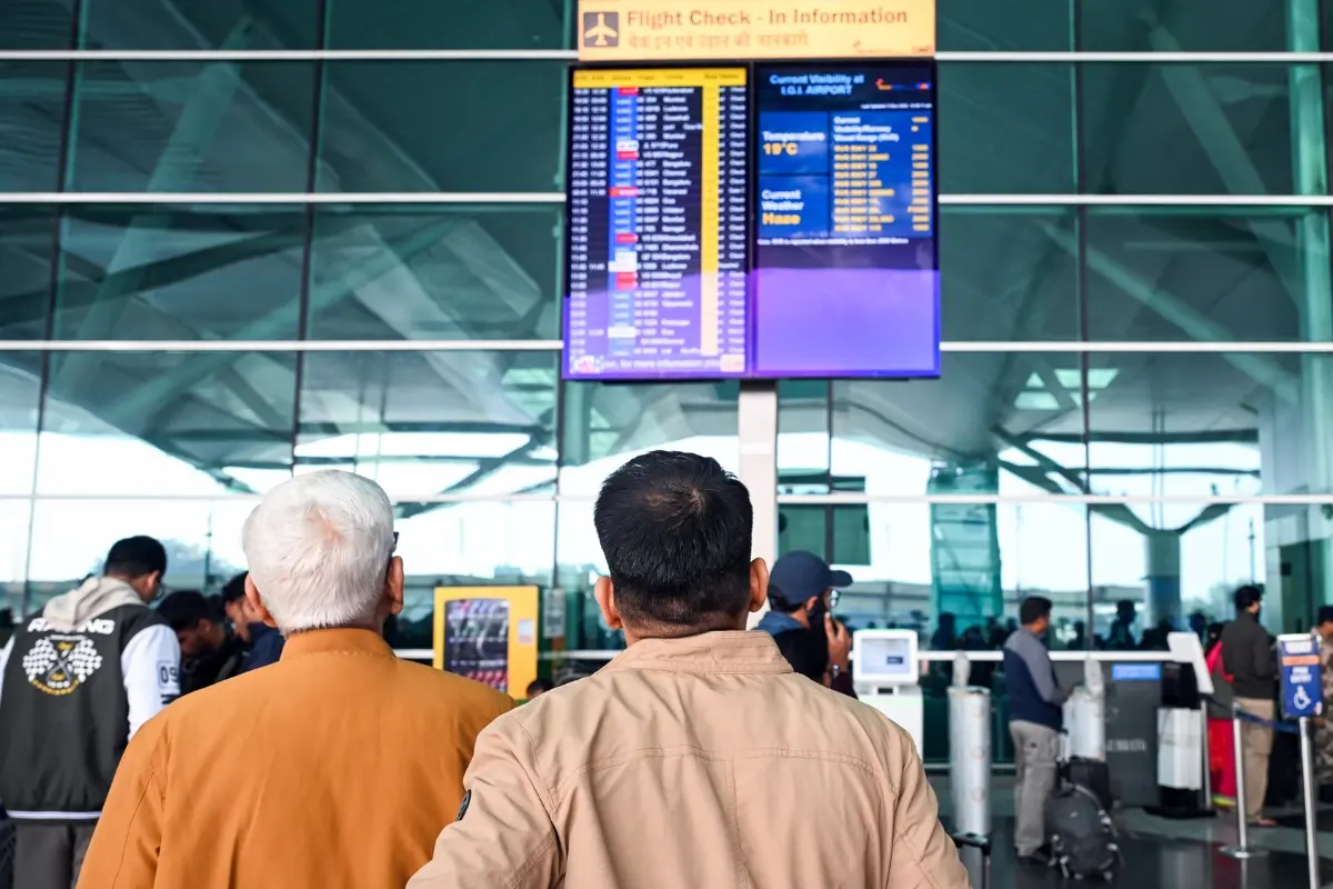 File Photo: Passengers look at a flight information display as many IndiGo flights stand cancelled at Indira Gandhi International Airport (IGI Airport) | ANI