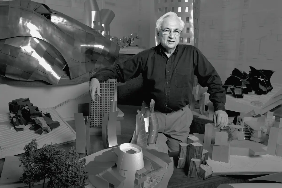 Architect Frank Gehry poses with miniatures of his designs in Los Angeles in 1989 | Photo: Bonnie Schiffman/Getty Images