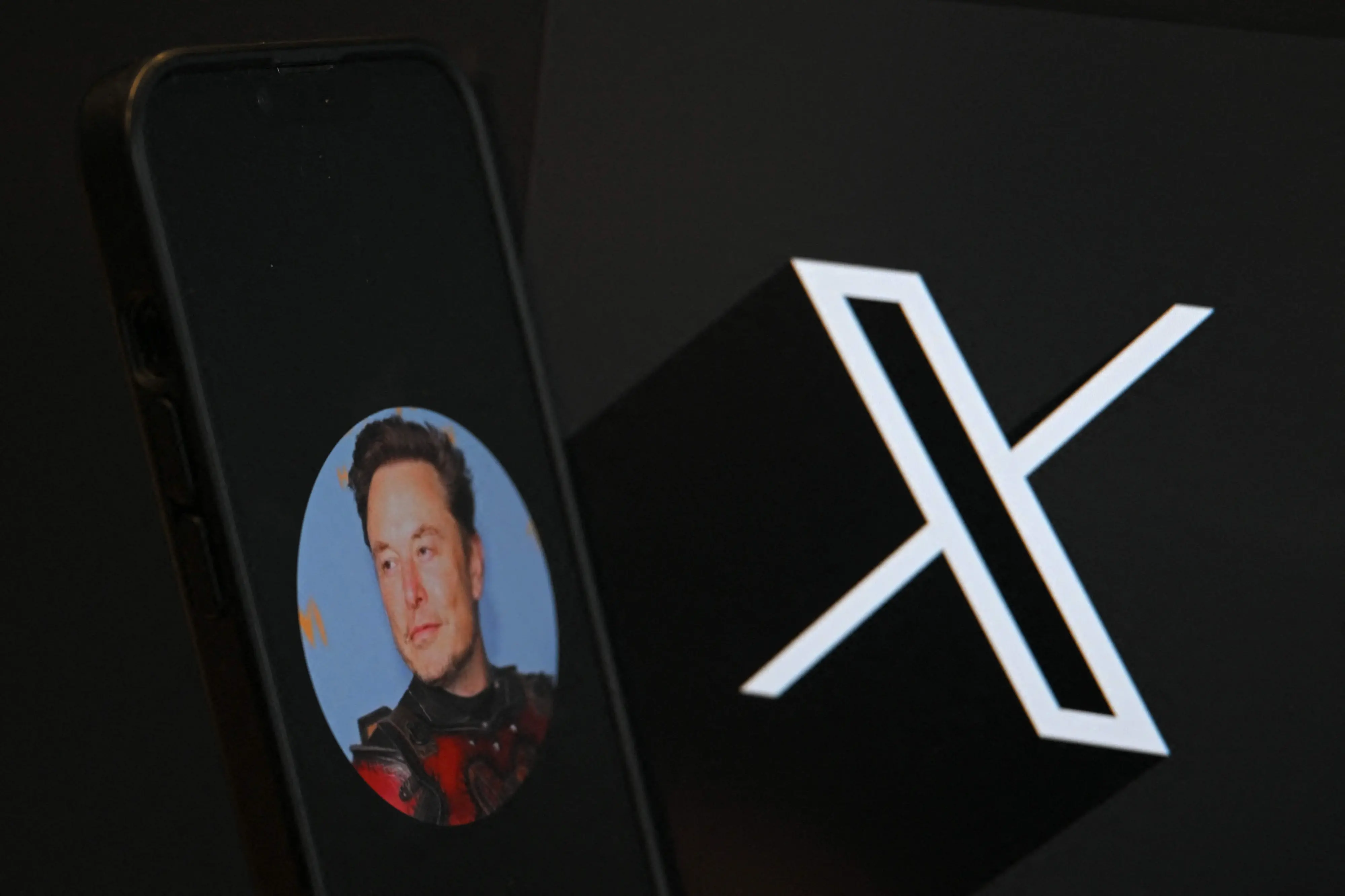 (FILES) This illustration photograph shows the logo of social network X (formerly Twitter) and a photograph of CEO of social network X, Elon Musk displayed on a smartphone in Brussels on September 27, 2024. The European Union hit Elon Musk's X with a 120-million-euro ($140-million) fine on December 5, 2025 for breaking its digital rules, in a move that risks a fresh clash with US President Donald Trump's administration. (Photo by Nicolas TUCAT / AFP)