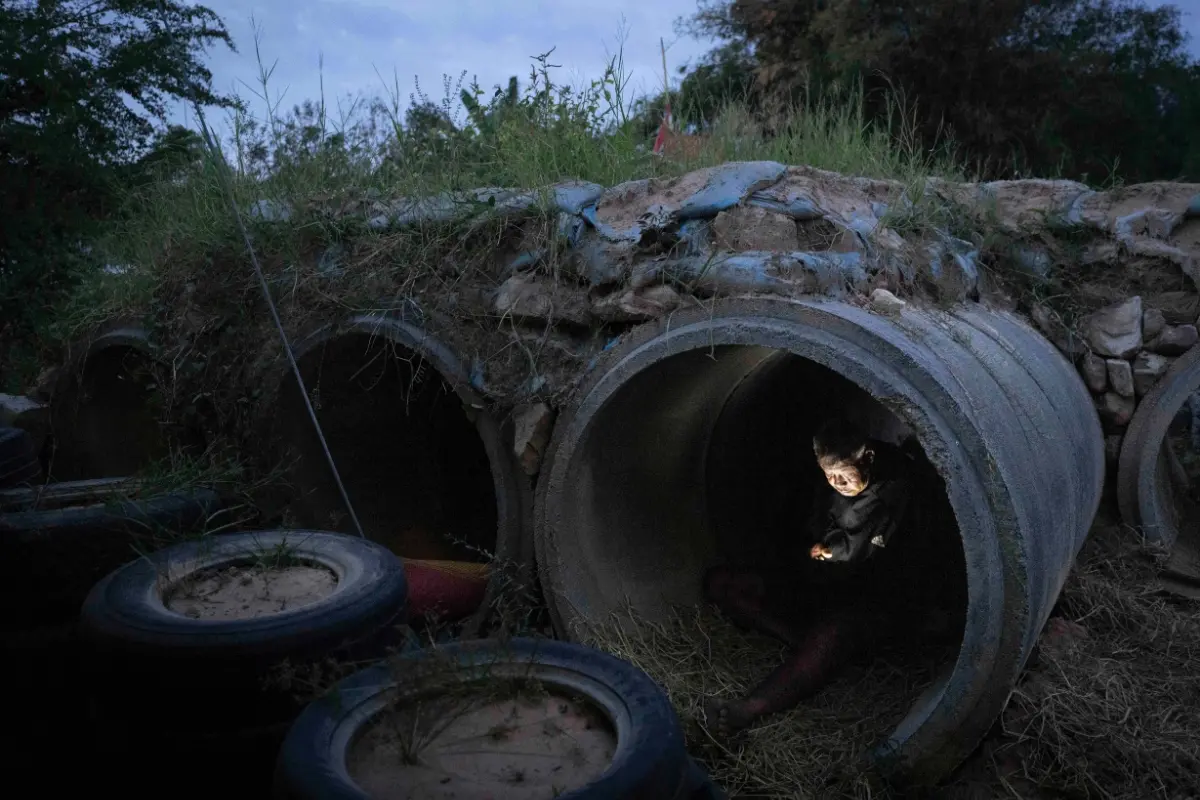 A Thai resident who fled clashes between Thai and Cambodian soldiers, uses mobile phone while taking shelter in Buriram province, Thailand | Photo: AP