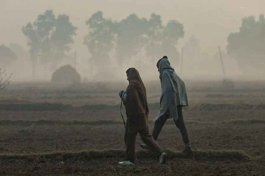 Villagers walk through a field on a cold winter morning, on the outskirts of Jammu