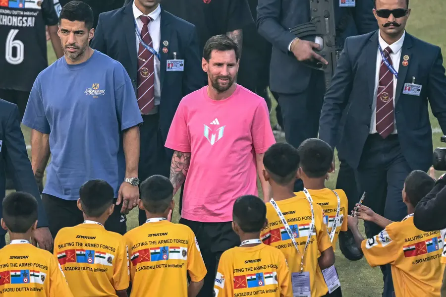Argentina's footballer Lionel Messi (C), along with Uruguayan footballer Luis Suárez (L), arrives to attend an event during his GOAT Tour at the Arun Jaitley Stadium in New Delhi