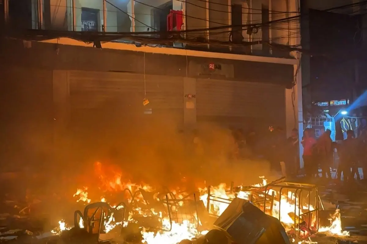 This frame grab from AFPTV video footage taken on December 19, 2025 shows smashed windows and a fire outside the Prothom Alo office in Dhaka, amid protests following the news of the death of youth leader Sharif Osman Hadi. (Photo by Maruf Hasan / AFPTV / AFP)