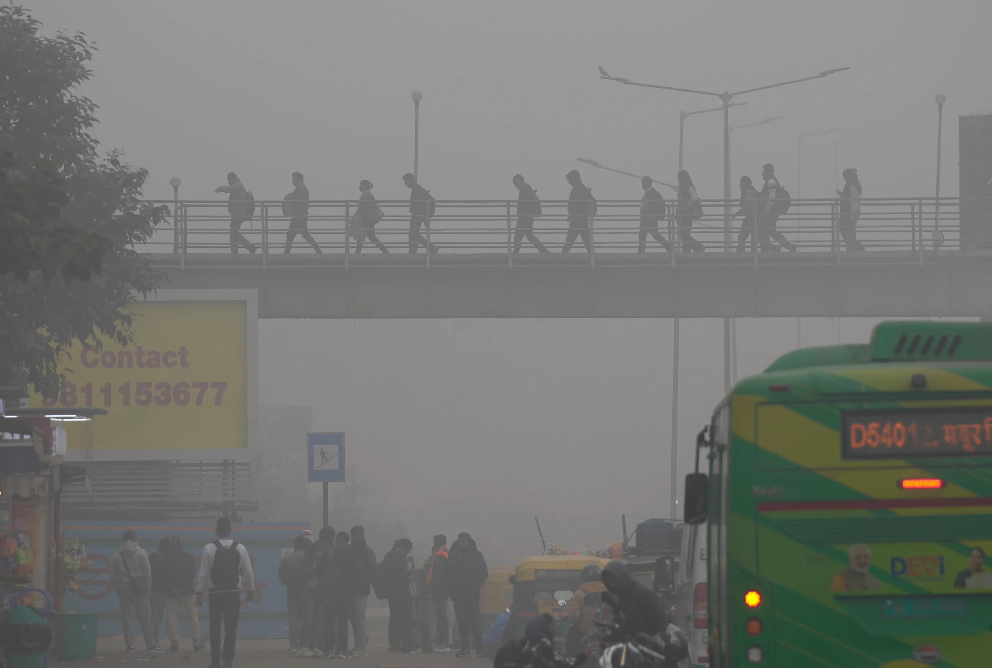 Commuters walk across a foot-over bridge amid dense fog on a winter morning, near Akshardham Temple, in New Delhi. | Photo: PTI