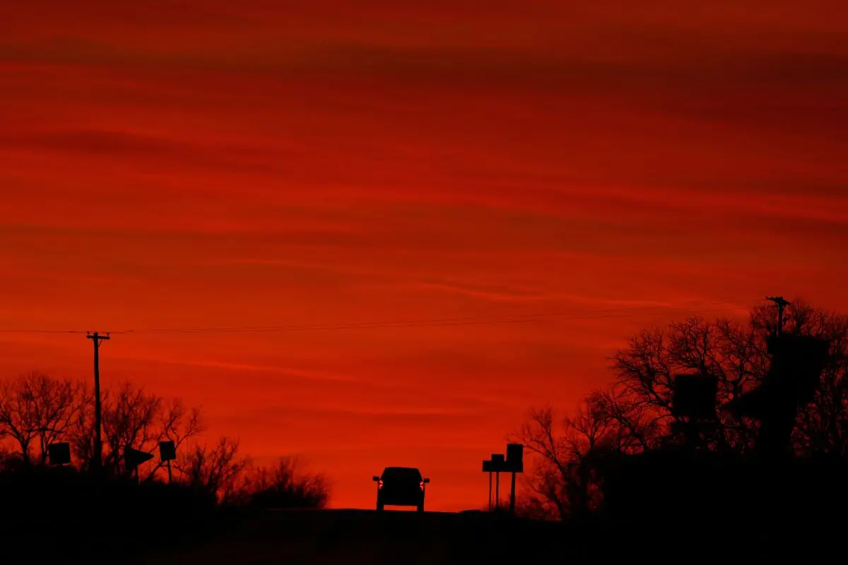 A motorist drives into the sunset on the last day of fall, Saturday, Dec. 20, 2025, near Edgerton, Kan. (AP Photo/Charlie Riedel)