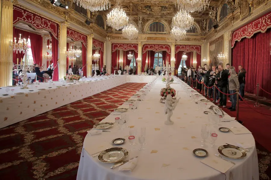 Visitors view a table dressed with plates and glasses for official dinners at the Elysee Palace in Paris