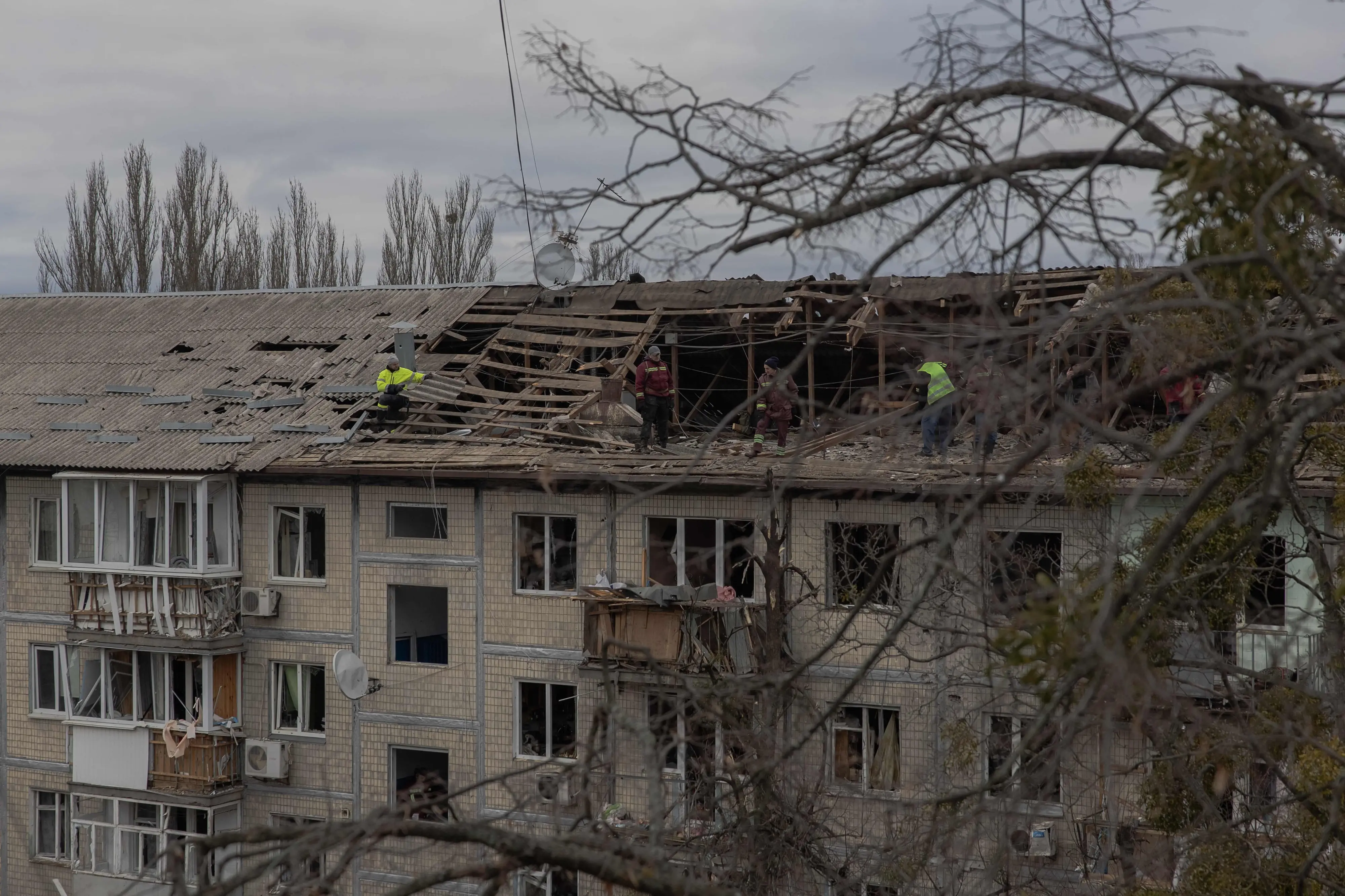 Workers clear debris from the roof of a heavily damaged residential building following a drone strike in Kyiv | AFP