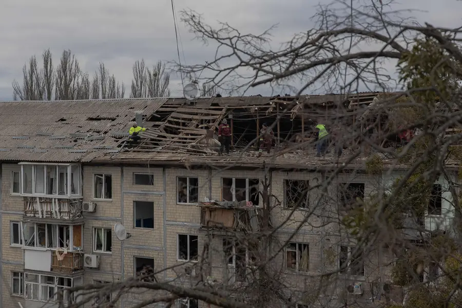 Workers clear debris from the roof of a heavily damaged residential building following a drone strike in Kyiv