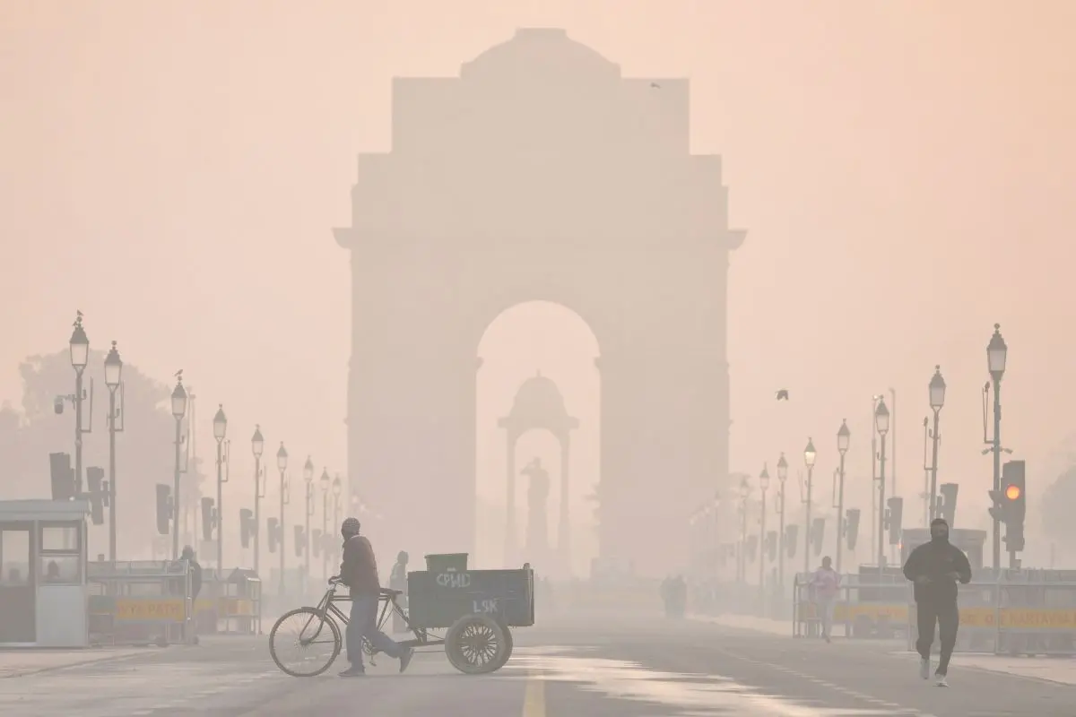The India Gate shrouded in a layer of smog as people make their way during a cold winter morning, at Kartavya Path, in New Delhi, Wednesday, Dec. 24, 2025. (CPCB).