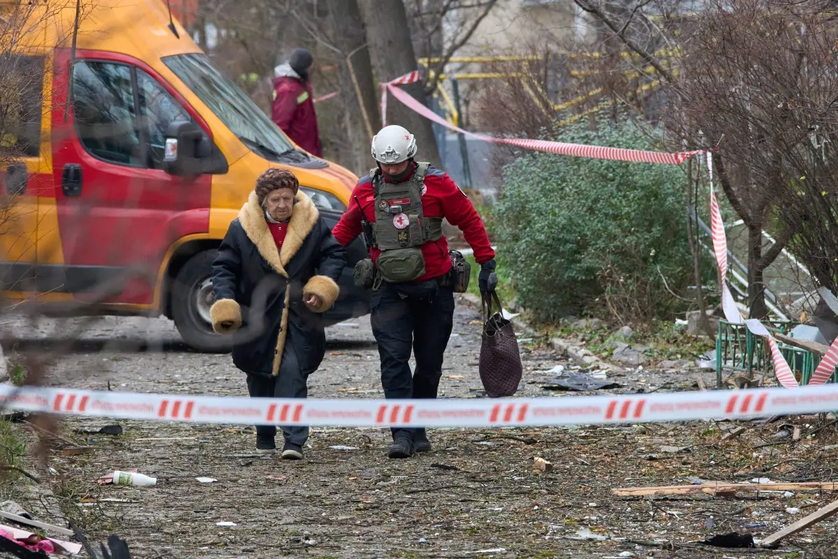 A paramedic evacuates an elderly resident after a Russian drone hit an apartment building during an aerial attack in Kyiv. | Photo: AP/PTI