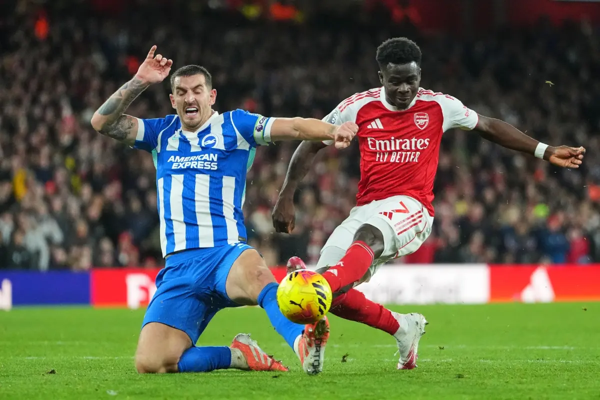 Arsenal's Bukayo Saka and Brighton's Lewis Dunk challenge for the ball during the English Premier League soccer match between Arsenal and Brighton | Photo: AP