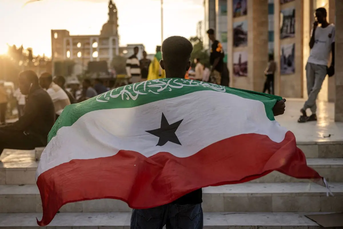A man holds a flag of Somaliland in front of the Hargeisa War Memorial monument. (Photo by LUIS TATO / AFP)