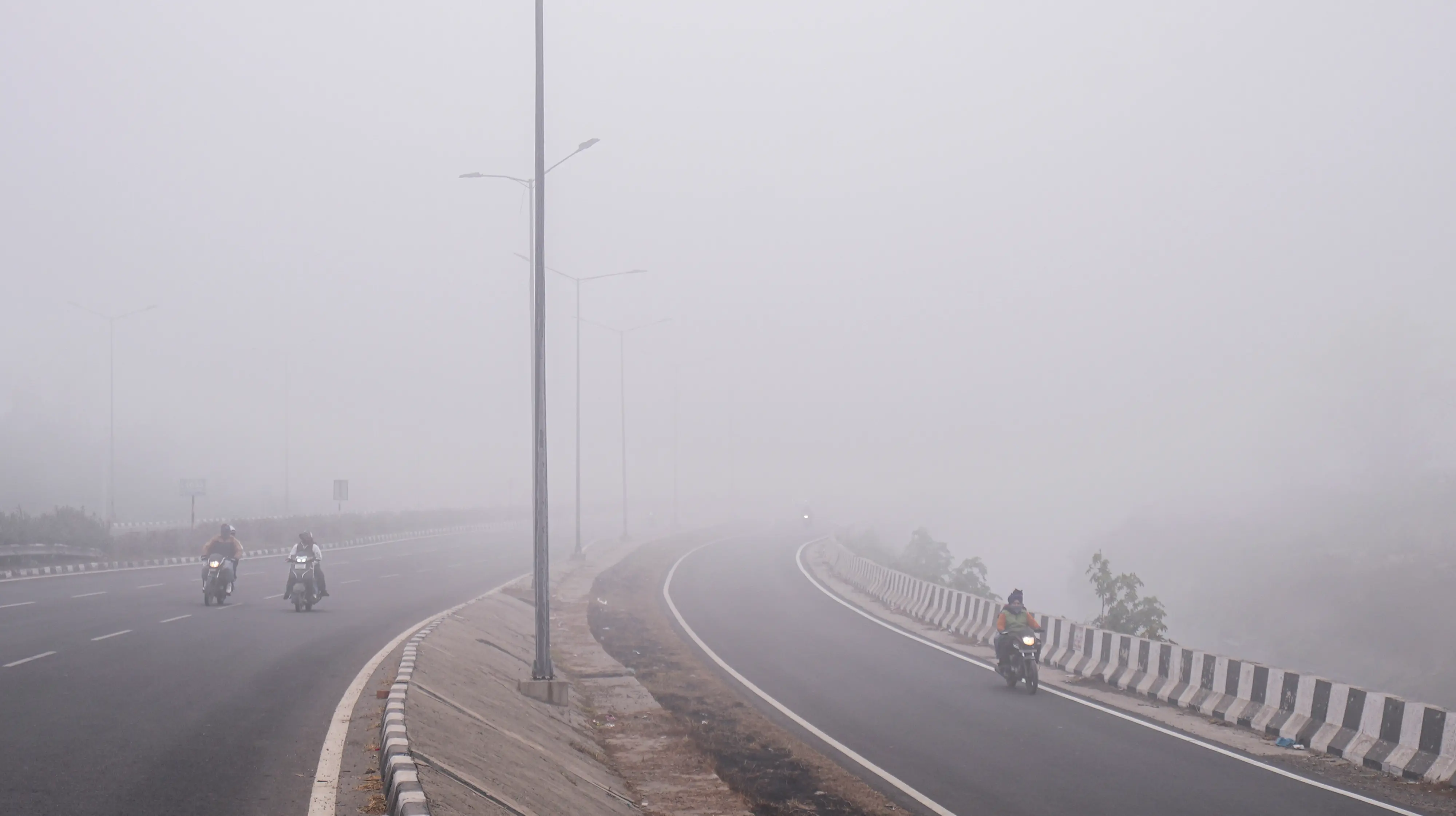 Motorcyclists proceed along a highway as dense fog reduces visibility across Punjab, in Amritsar | PTI