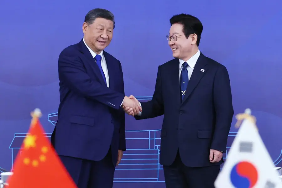 Chinese President Xi Jinping, left, shakes hands with South Korean President Lee Jae Myung