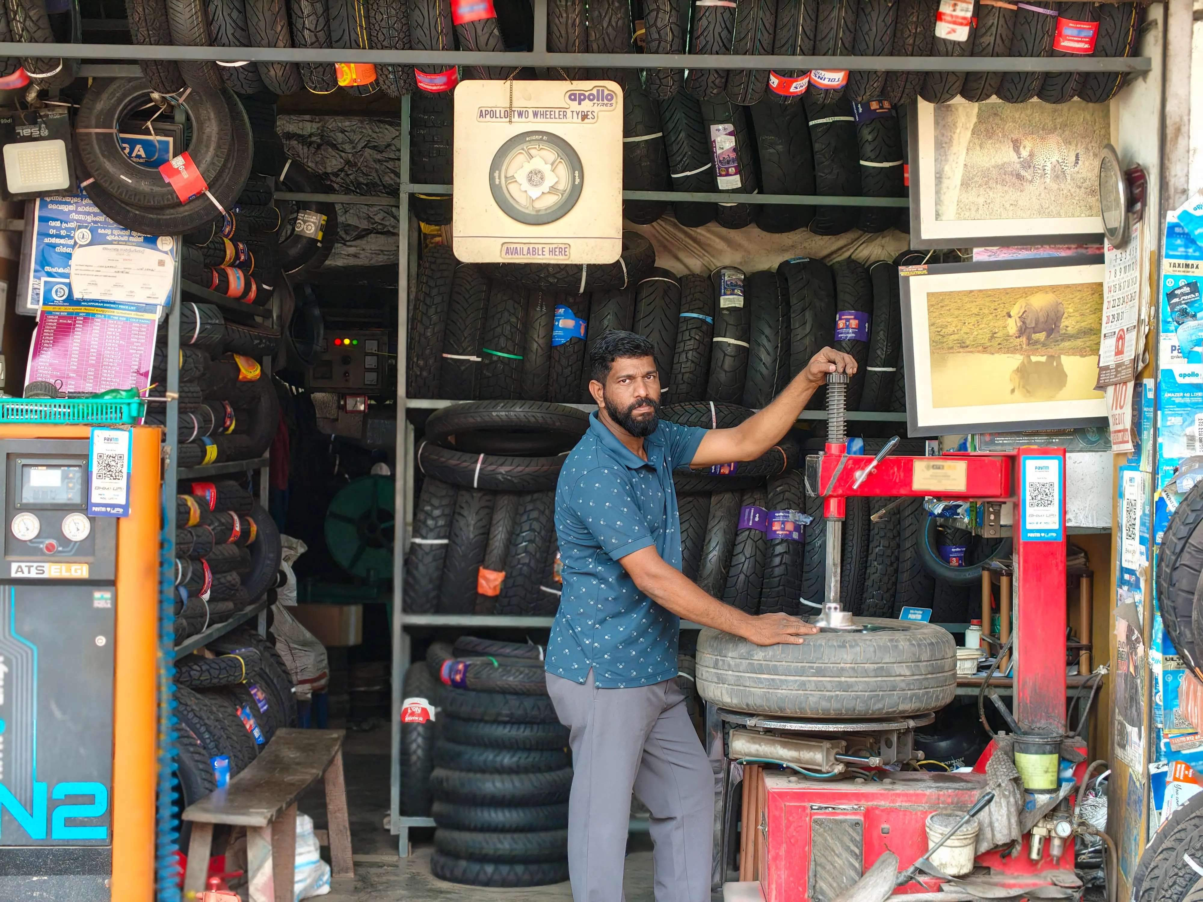 Sathrajith at his tyre shop. Two of his wildlife photographs can be seen on the adjoining pillar | Photo: Special arrangement courtesy Sathrajith Karad