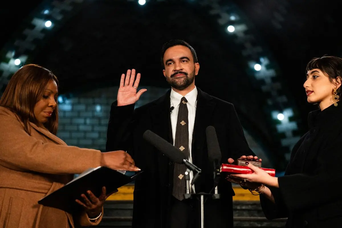 New York mayor-elect Zohran Mamdani (C) places his hand on a Quran as he is sworn in by New York Attorney General Letitia James (L), and his wife Rama Duwaji looks on in New York, on January 1, 2026. (Photo by Amir Hamja / POOL / AFP)