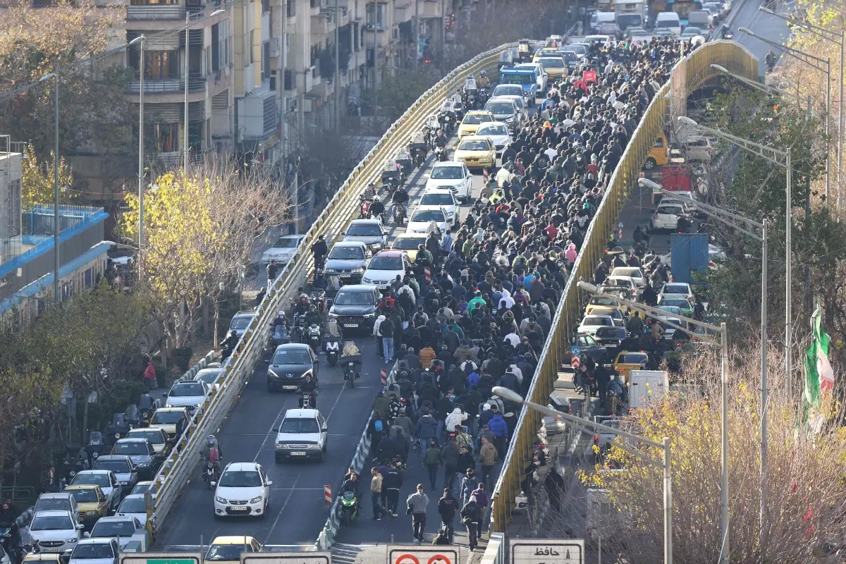 File: Shopkeepers and traders walk over a bridge during a protest | Photo: AFP