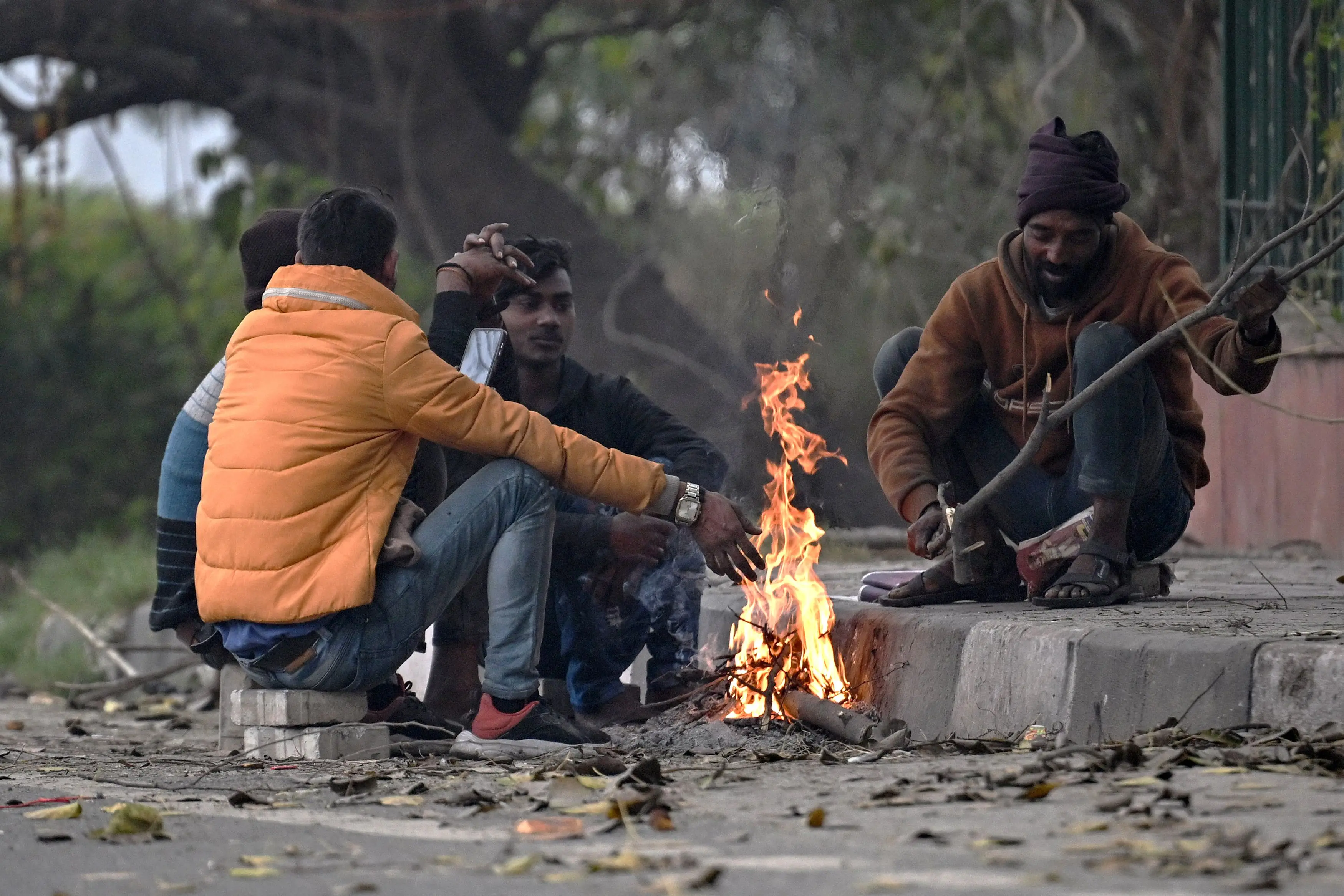 People sit around a bonfire to warm themselves on a cold winter morning in New Delhi on January 1, 2026 | Photo: AFP
