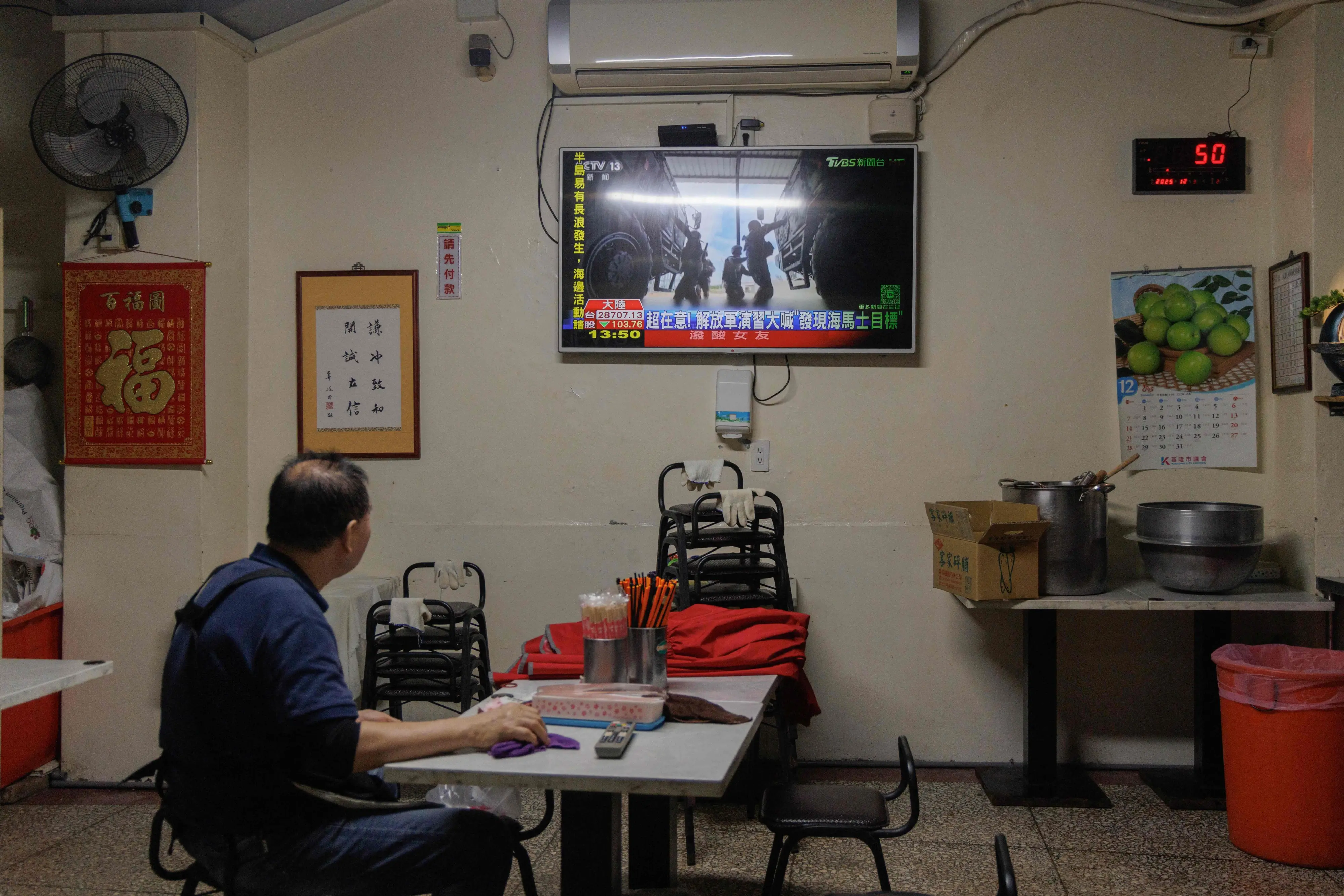 A man watches TV news coverage of the Chinese People's Liberation Army (PLA) military drills around Taiwan in Keelung | AFP