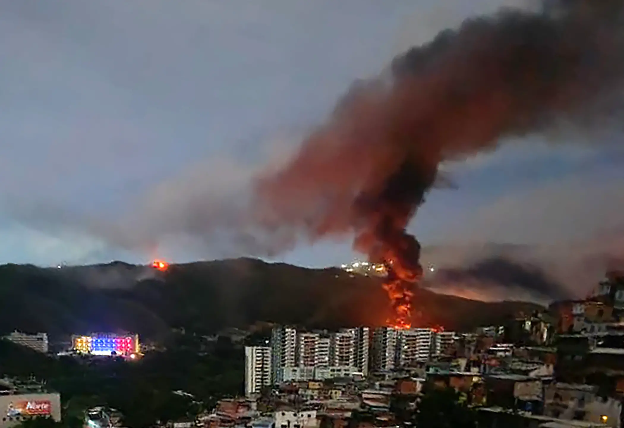 Fire at Fuerte Tiuna, Venezuela's largest military complex, is seen from a distance after a series of explosions in Caracas on January 3, 2026. | AFP