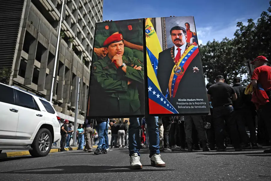 A supporters of Venezuela's President Nicolas Maduro holds a portrait of him and another of late Venezuela's leader Hugo Chavez in Caracas
