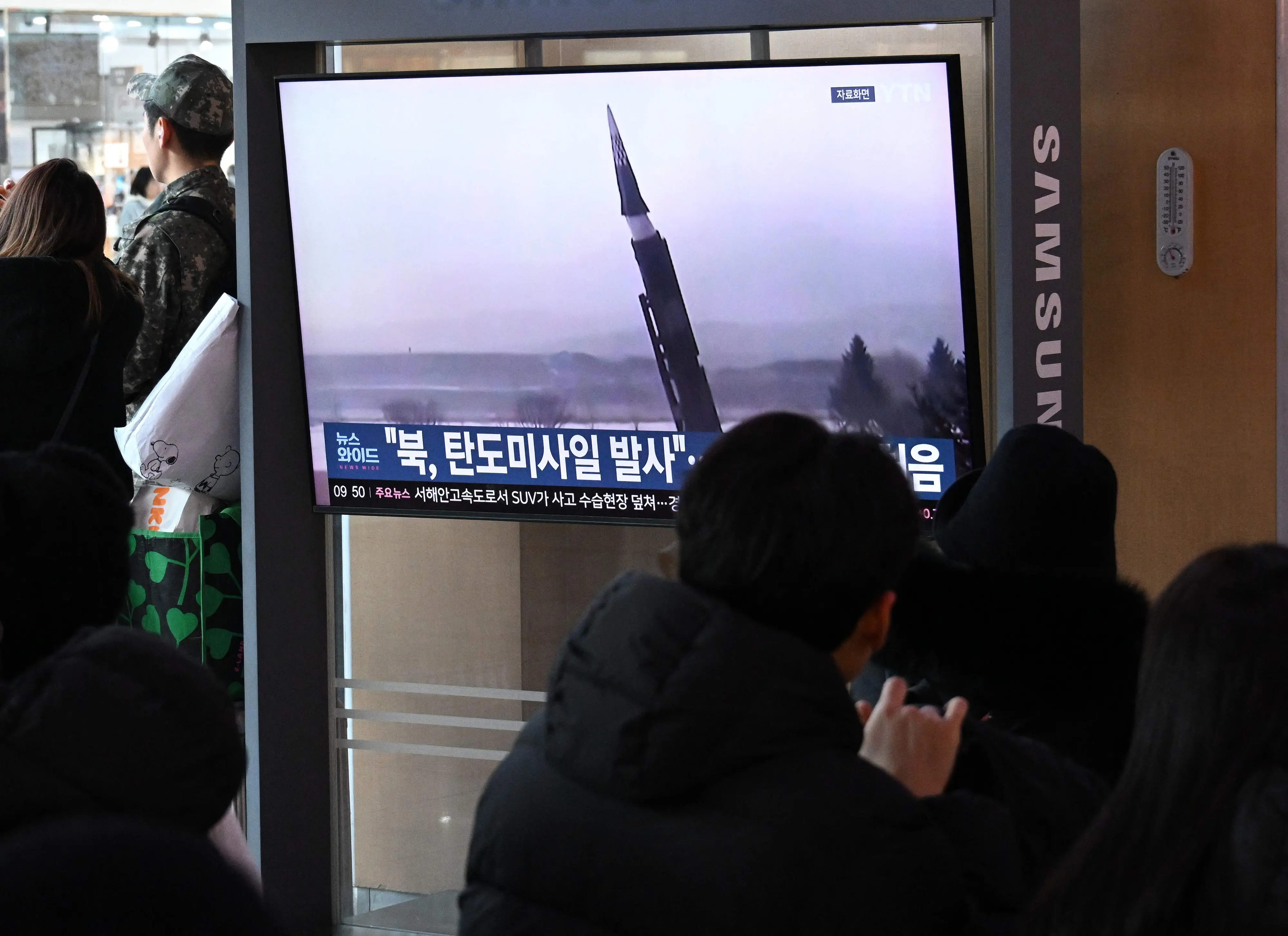 People sit in front of a television screen showing a news broadcast with file footage of a North Korean missile test, at a train station in Seoul on January 4 | Photo: AFP