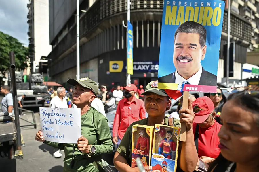 A supporter of ousted Venezuela's President Nicolas Maduro holds a poster of him and toys of him and his wife, Cilia Flores