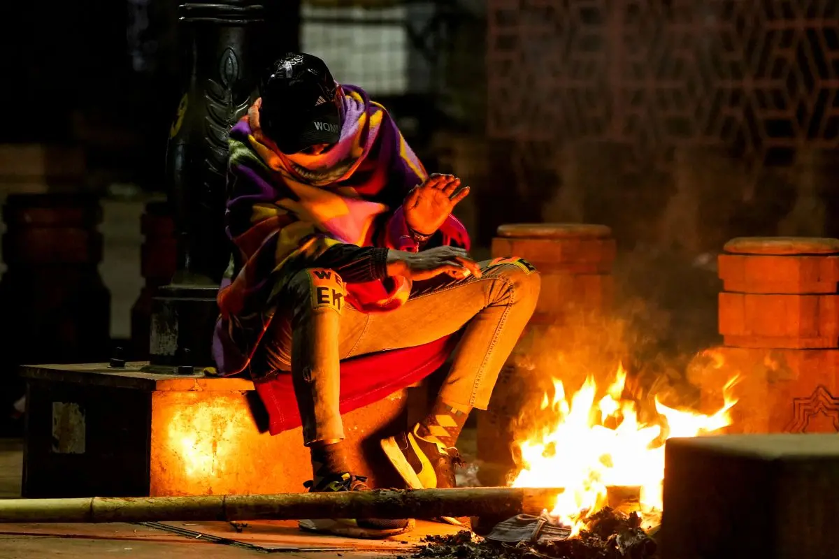 A man warms himself near a bonfire on a cold winter morning, in New Delhi, Monday, Jan. 5, 2026. (PTI Photo/Money Sharma)