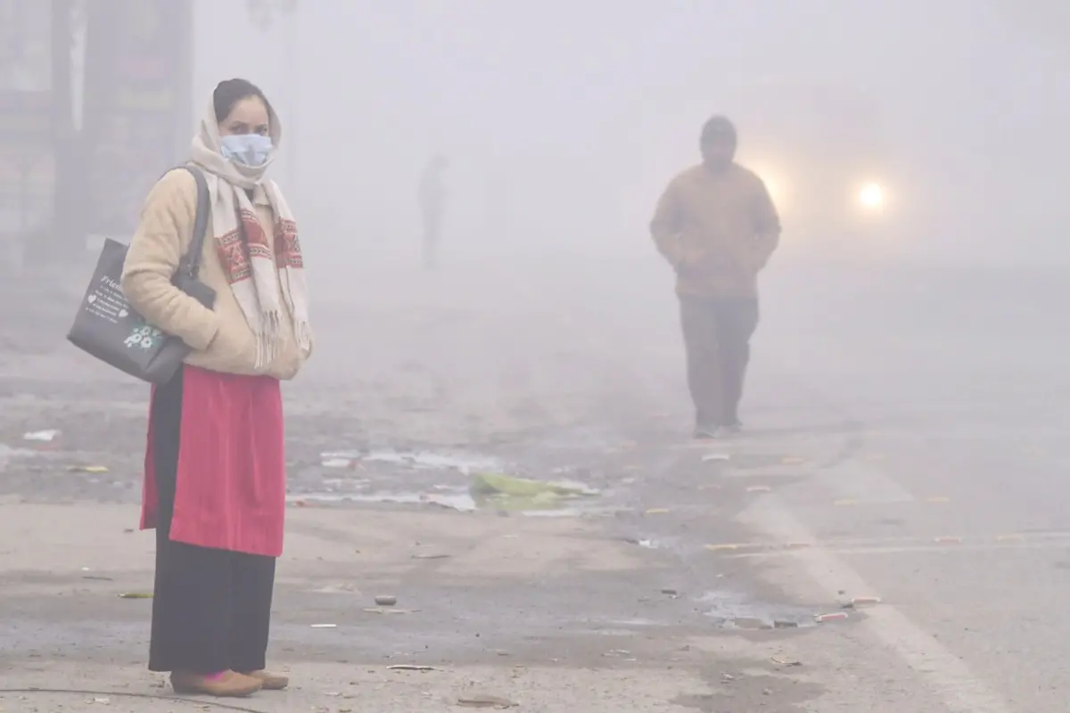 People on a road enveloped in dense fog on a cold winter morning
