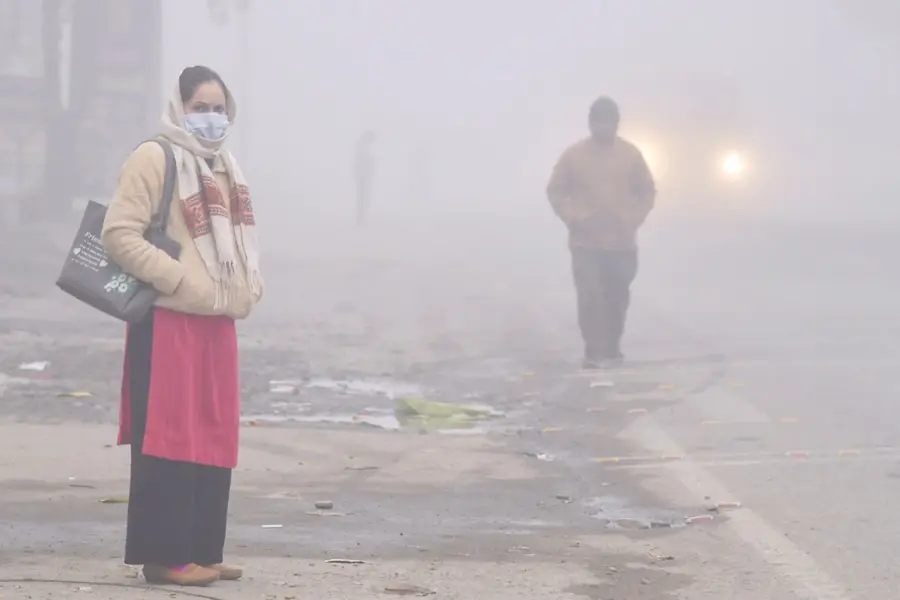 People on a road enveloped in dense fog on a cold winter morning