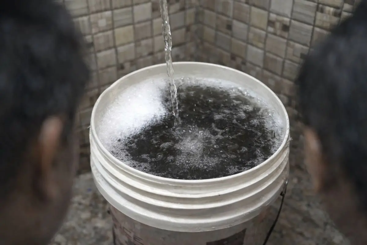 Contaminated, foul-smelling water flowing into a bucket from a household tap, highlighting the severity of the drinking water crisis in several parts of Delhi.