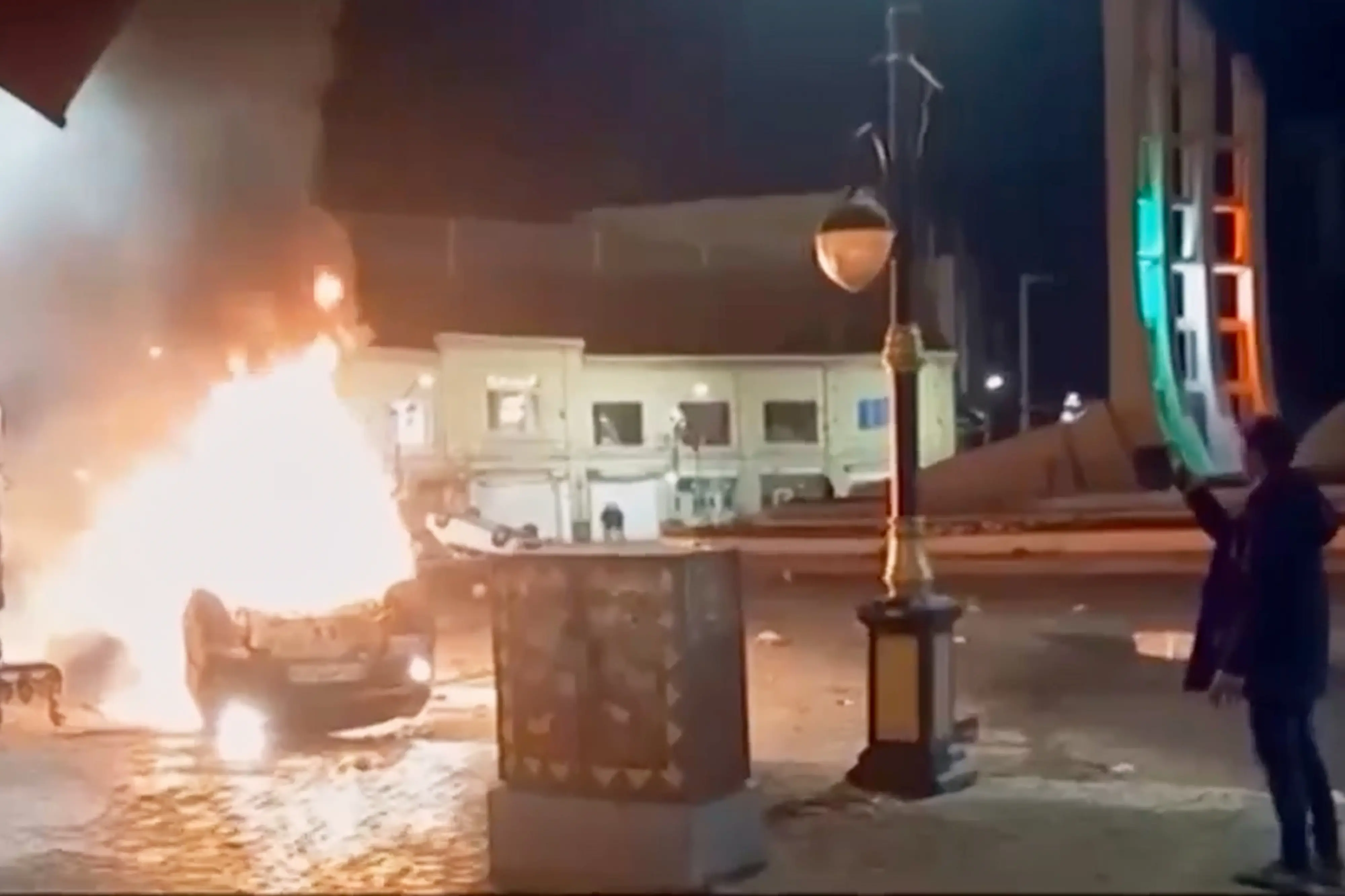 This frame grab from a video released Friday, Jan. 9, 2026, by Iranian state television shows a man holding a device to document burning vehicles during a night of mass protests in Zanjan, Iran. | Photo: AP