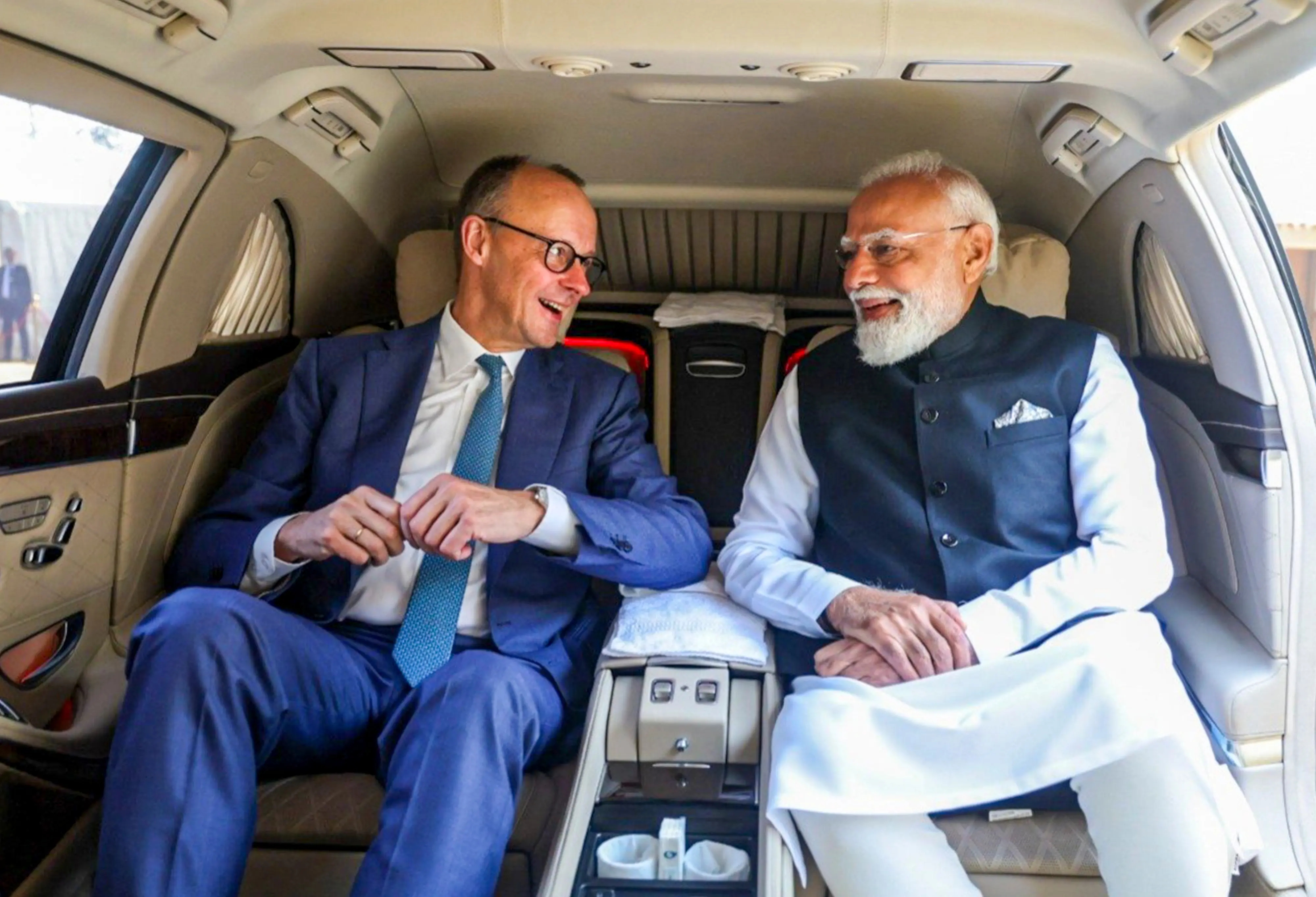 Prime Minister Narendra Modi and German Chancellor Friedrich Merz share a light moment during their interaction while travelling together, in Gujarat. | Photo: PTI